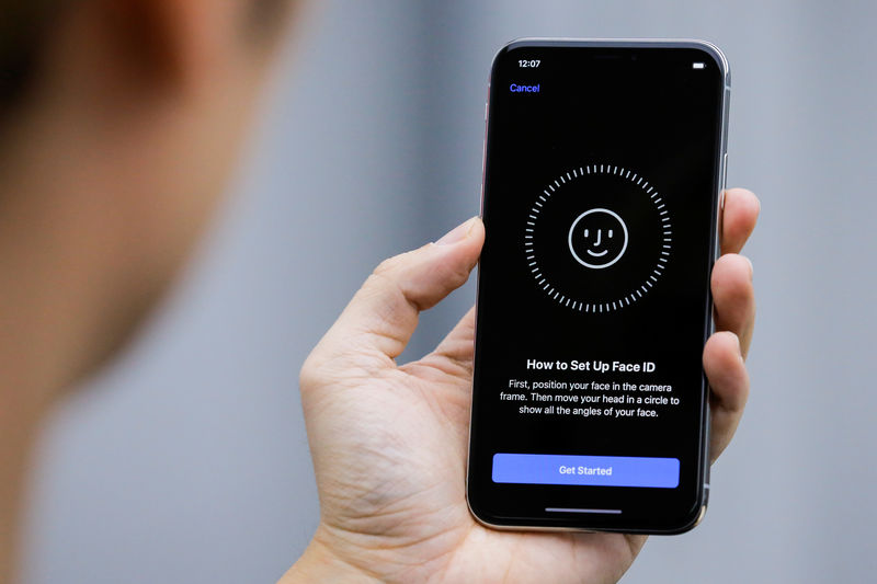 FILE PHOTO:  An attendee uses the Face ID function on the new iPhone X during a presentation for the media in Beijing